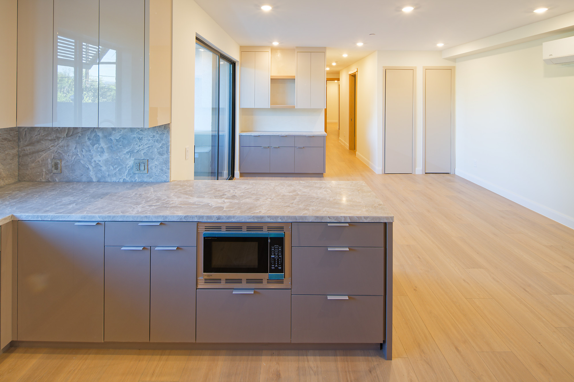 Open living area with stone kitchen counters, built-in microwave, and balcony doors at The Benjamin in Lake Balboa