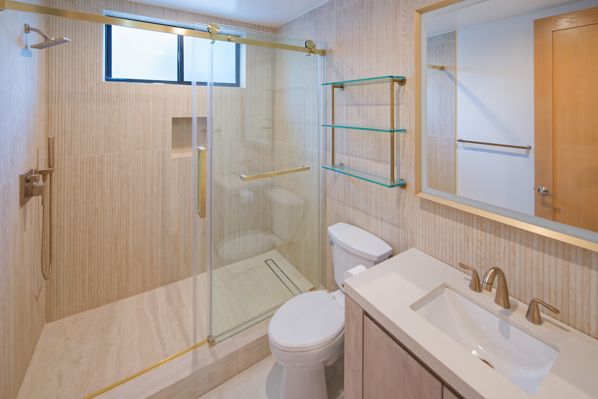 Bathroom with a glass shower, textured tile, glass shelving, and a wood vanity at The Benjamin in Lake Balboa